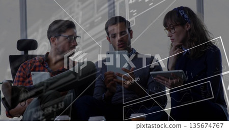 Colleagues collaborating on tablets in modern office lounge with coffee cup and data overlays 135674767