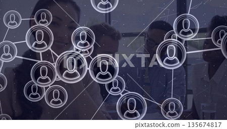 Collaborating professionals reviewing files at conference table in boardroom, with network overlay 135674817