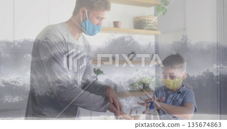 Applying hand sanitizer at modern home kitchen counter, with pump bottle next to white cabinets 135674863