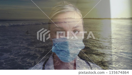 Blending doctor wearing face mask in double-exposure with coastal sunset waves, with stethoscope 135674864