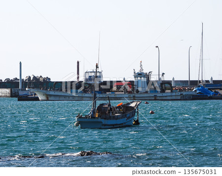 A fishing boat anchored in the port 135675031