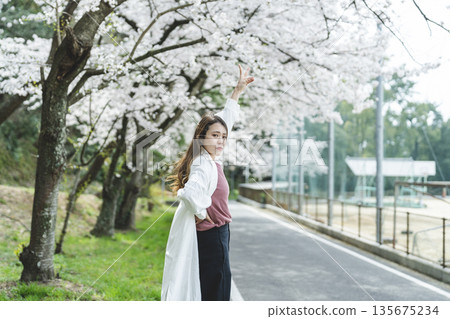 沿著櫻花樹散步的年輕女子 沿著櫻花樹散步的年輕女子 135675234