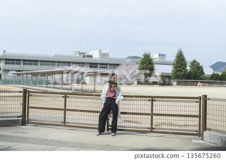 一位年輕女子走在她的母校門前 135675260