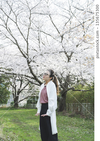 Young woman walking along cherry blossom trees Young woman walking along cherry blossom trees 135675300
