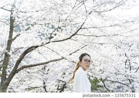 沿著櫻花樹散步的年輕女子 135675331
