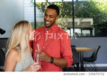Couple celebrating at home, smiling and holding champagne glasses, enjoying moment 135675732