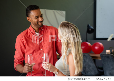 Couple celebrating with champagne glasses, sharing joyful moment at home 135675738