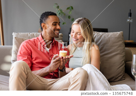 Celebrating with cupcake and candle, couple smiling in special moment together 135675748
