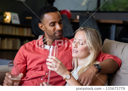 Couple relaxing on sofa, enjoying champagne and sharing intimate moment at home Couple relaxing on sofa, enjoying champagne and sharing intimate moment at home 135675779