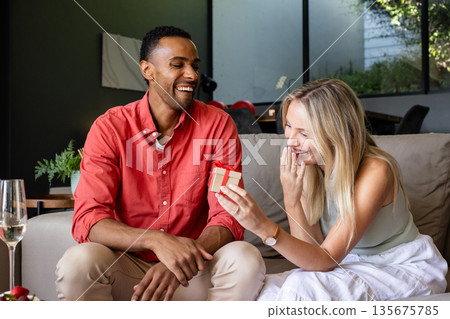 Couple exchanging gifts at home, smiling and enjoying joyful moment together 135675785