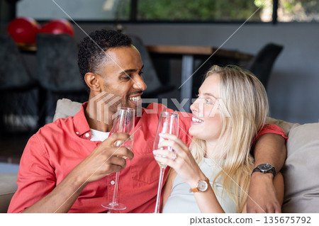 Couple celebrating at home, smiling and toasting with champagne glasses Couple celebrating at home, smiling and toasting with champagne glasses 135675792