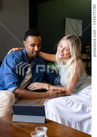 Happy couple watching tablet together at home, sharing joyful moments 135675798