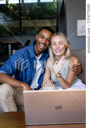 Happy couple video chatting on laptop at home, waving and smiling warmly 135675840