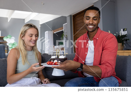 Smiling friends celebrating birthday at home, sharing cake and enjoying together 135675851