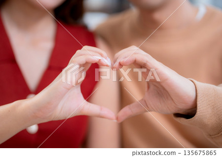 Close up hand heart shape of asian couple together in living room at home, showing love symbol. 135675865