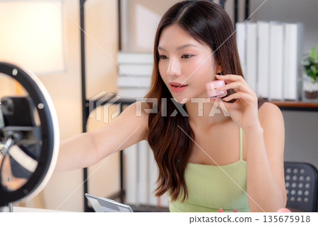 Young asian woman presenting and review cosmetic product with excitement on social media. 135675918