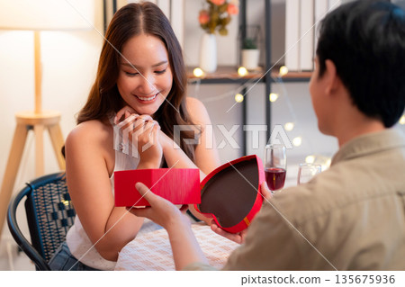 Romantic asian man giving heart shape gift box to girlfriend, surprise for Valentine's Day. 135675936