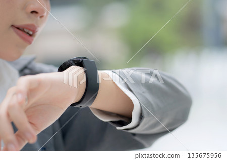 Close up young asian businesswoman in city talking to smartwatch using voice command with AI. Close up young asian businesswoman in city talking to smartwatch using voice command with AI. 135675956
