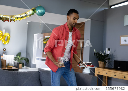 Man carrying cupcakes and drinks at home during birthday celebration Man carrying cupcakes and drinks at home during birthday celebration 135675982