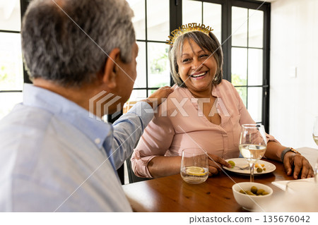 Celebrating birthday, African American woman smiling with friend at dining table Celebrating birthday, African American woman smiling with friend at dining table 135676042