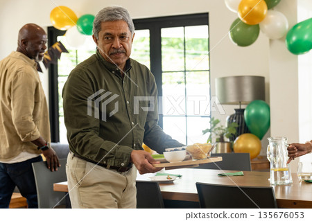 Man carrying tray with snacks at home during festive celebration with friends Man carrying tray with snacks at home during festive celebration with friends 135676053