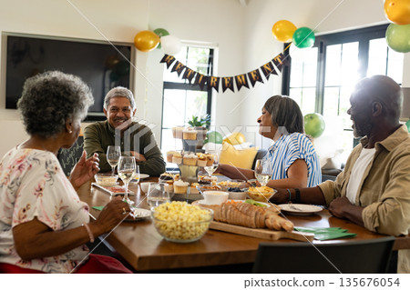 African American family celebrating at home, enjoying food and conversation together African American family celebrating at home, enjoying food and conversation together 135676054