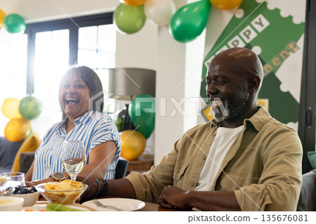 Smiling couple enjoying festive celebration with balloons and wine at home 135676081