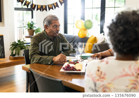 Senior man enjoying conversation at dining table during festive family gathering Senior man enjoying conversation at dining table during festive family gathering 135676090