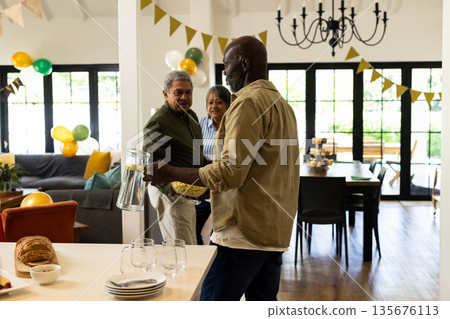 Friends preparing for celebration at home, setting table with drinks and snacks Friends preparing for celebration at home, setting table with drinks and snacks 135676113