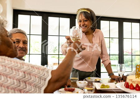 Elderly woman toasting with friends at home, celebrating with joy and laughter Elderly woman toasting with friends at home, celebrating with joy and laughter 135676114