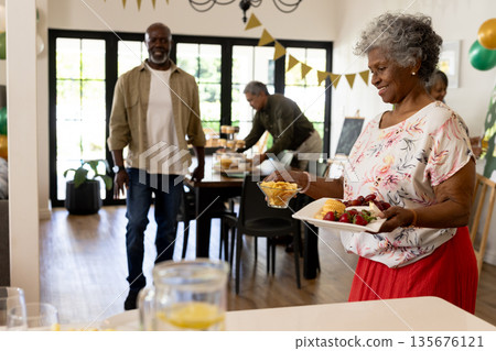 Elderly woman serving snacks at family gathering, smiling and enjoying celebration Elderly woman serving snacks at family gathering, smiling and enjoying celebration 135676121
