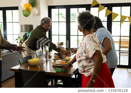 Family gathering around dining table sharing snacks and enjoying festive celebration 135676126