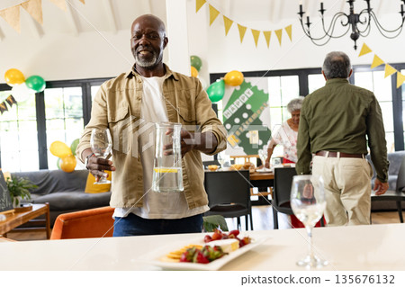 Man serving drinks at festive family gathering, smiling and enjoying celebration 135676132