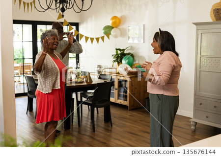 Celebrating birthday at home, elderly couple with family and festive decorations Celebrating birthday at home, elderly couple with family and festive decorations 135676144