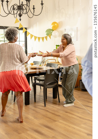 Elderly women enjoying festive gathering, exchanging gifts in decorated dining room Elderly women enjoying festive gathering, exchanging gifts in decorated dining room 135676145