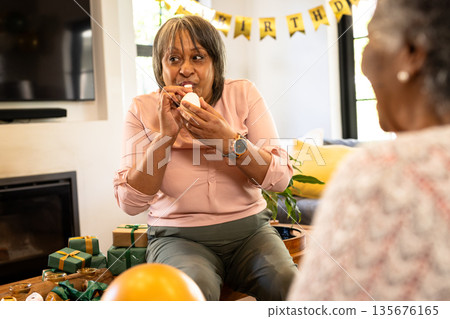 Woman joyfully biting cupcake at birthday party with gifts and decorations 135676165