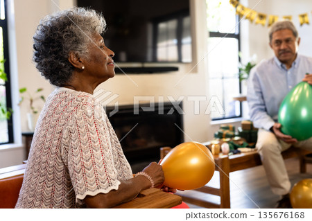 Elderly woman holding balloon, enjoying celebration with family at home 135676168
