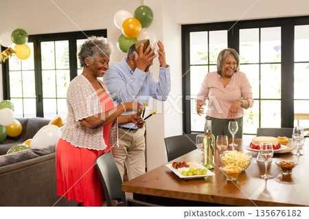 Seniors joyfully celebrating at home with food, drinks, and festive decorations Seniors joyfully celebrating at home with food, drinks, and festive decorations 135676182