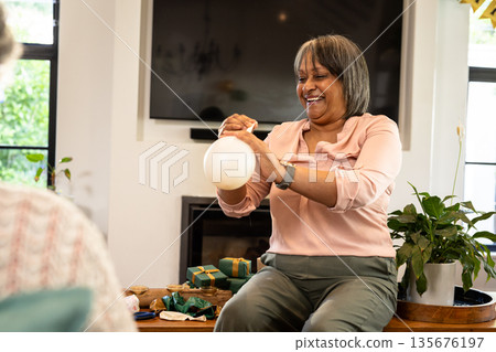 African American woman joyfully inflating balloon at home during celebration African American woman joyfully inflating balloon at home during celebration 135676197