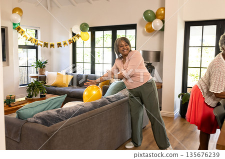 African American woman decorating living room with balloons for birthday celebration African American woman decorating living room with balloons for birthday celebration 135676239