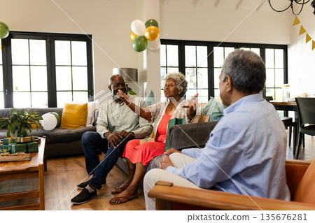 Elderly friends enjoying conversation and laughter at home during festive gathering Elderly friends enjoying conversation and laughter at home during festive gathering 135676281