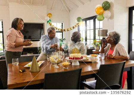 Family celebrating birthday with cake and gifts in cozy living room setting Family celebrating birthday with cake and gifts in cozy living room setting 135676292