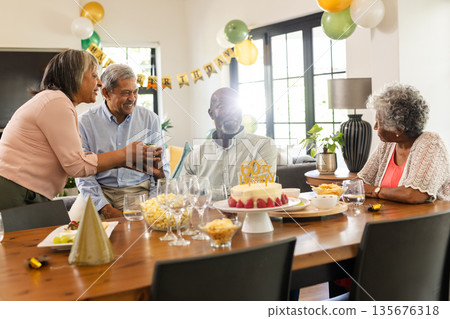 Family celebrating 60th birthday with cake and decorations at home, sharing joy Family celebrating 60th birthday with cake and decorations at home, sharing joy 135676318