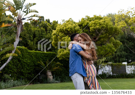 Young couple embracing in lush garden, enjoying peaceful moment together Young couple embracing in lush garden, enjoying peaceful moment together 135676433