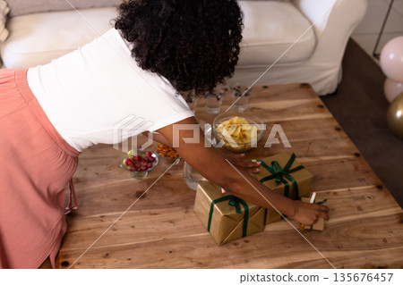 Woman arranging wrapped gifts on wooden table for celebration at home 135676457