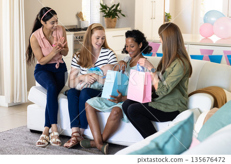 Friends celebrating at home, giving gifts and enjoying joyful moment together Friends celebrating at home, giving gifts and enjoying joyful moment together 135676472