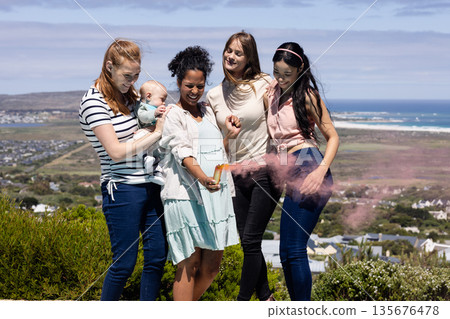 Friends celebrating outdoors with colorful powder, enjoying joyful moments together Friends celebrating outdoors with colorful powder, enjoying joyful moments together 135676478