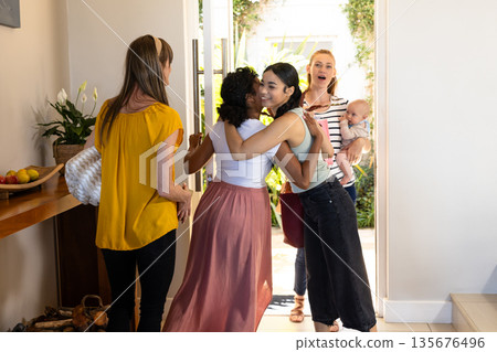 Friends greeting each other warmly at home, sharing joyful hugs and smiles Friends greeting each other warmly at home, sharing joyful hugs and smiles 135676496