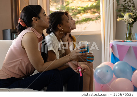 Friends celebrating at home, holding drinks and smiling with festive decorations 135676522
