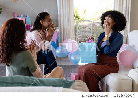 Women celebrating baby shower at home, exchanging gifts and sharing joyful moments Women celebrating baby shower at home, exchanging gifts and sharing joyful moments 135676564